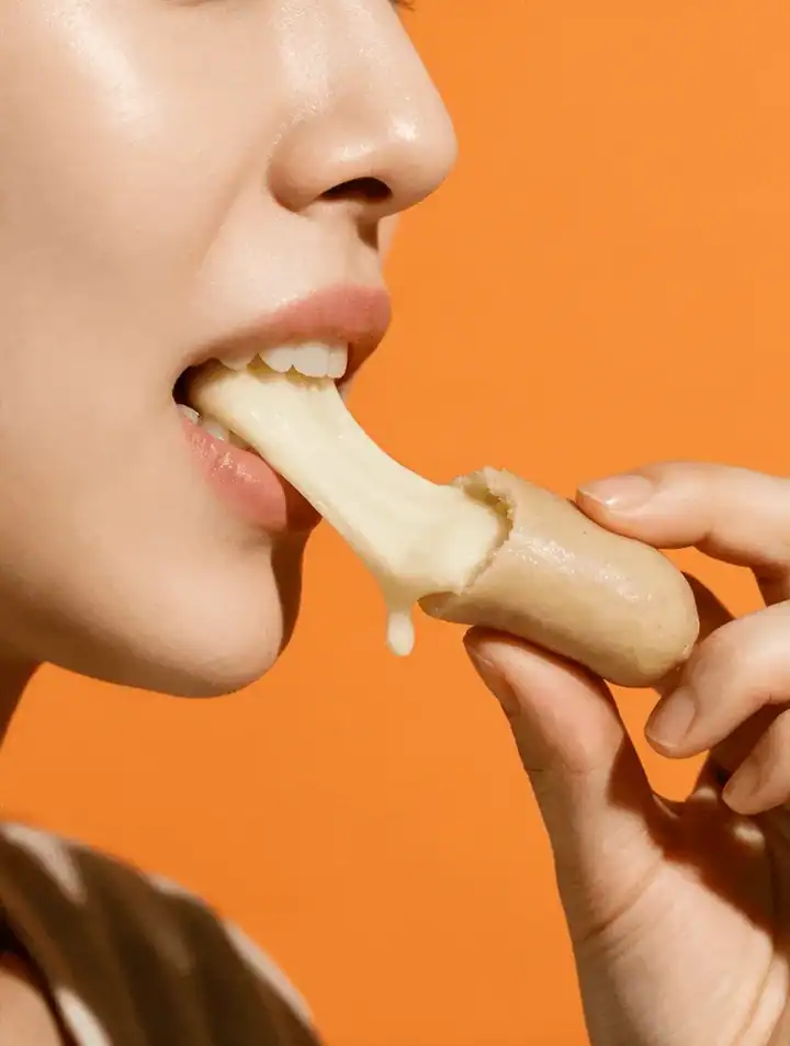A person biting into tteok with stretching cheese